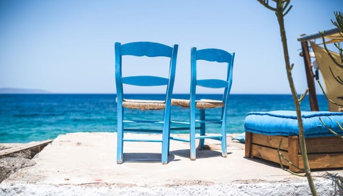 Two blue chairs in front of beach